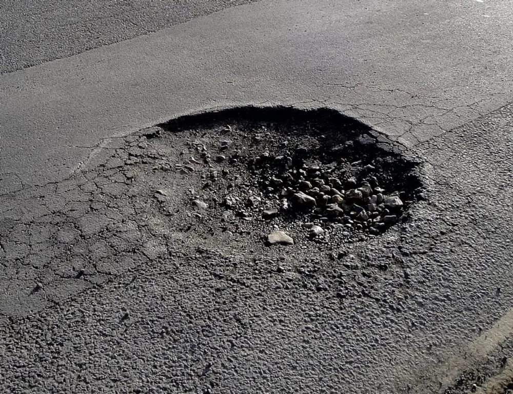Bache abierto en una carpeta asfáltica antes de ser reparado.